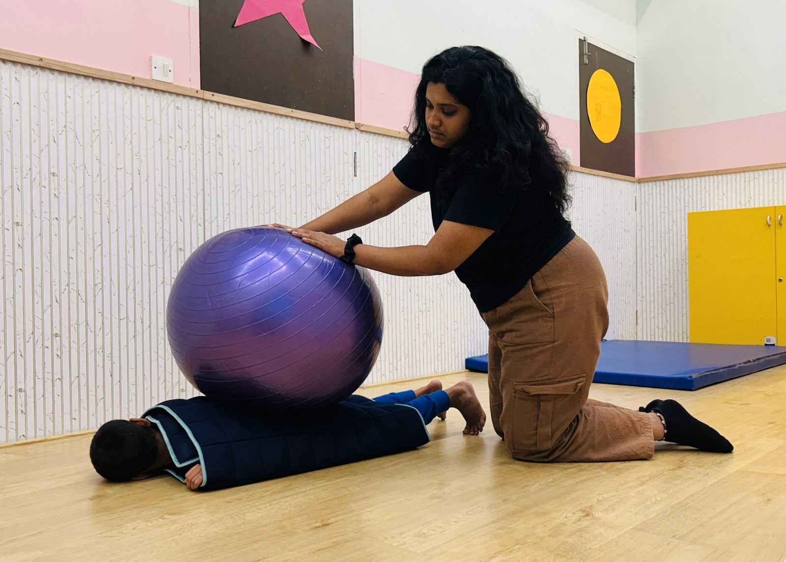 A team member working with a child on a therapy ball