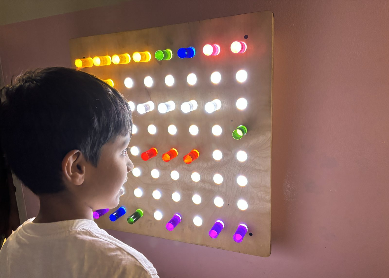 A child exploring a light pegboard